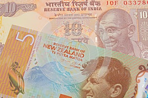 A orange ten rupee bill from India paired with a orange, plastic five dollar bill from New Zealand.