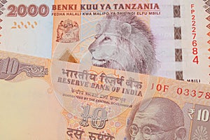 A orange ten rupee bill from India paired with a orange and white 2000 shilling bill from Tanzania.