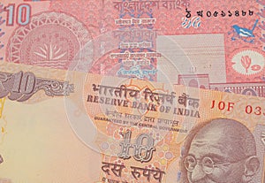 A orange ten rupee bill from India paired with a red ten taka bank note from Bangladesh.