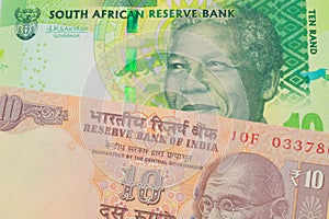 A orange ten rupee bill from India paired with a shiny, green 10 rand bill from South Africa.