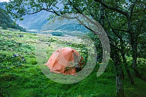 An orange tent during a hiking trip in Folgefonna National Park, Norway. Sleeping in tent in mountains.