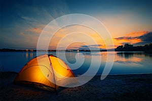 Orange tent on the lake at dusk