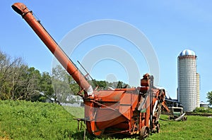 Orange threshing machine on Amish farm
