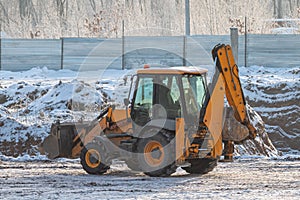 Orange tractor excavator at construction site in winter
