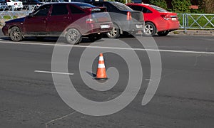 an orange traffic cone on the road indicates the path, road works, detour of a dangerous section of road, roadway repairs