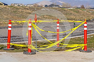 Orange traffic poles with yellow caution tape surrounding a hole on the ground