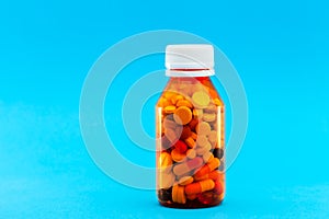 Orange transparent bottle for medicines filled with different pills.