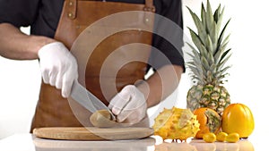 The orange tropical fruit composition consisted of pineapple, kiwano and persimmons. The cooker is cutting the tasty