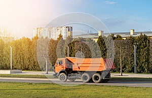 Orange truck dump with an empty body rides on the highway or at the interurban road