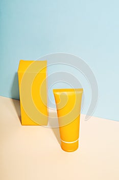Orange tube and box of sunscreen on  blue background. Sun Protection. Copy space