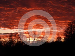 Orange twilight clouds light up sun pillar in winter sunset