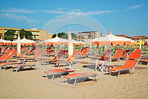 Orange umbrellas and chaise lounges on the beach of Rimini in It