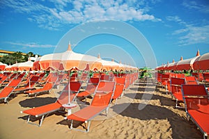 Orange umbrellas and chaise lounges on the beach of Rimini in It