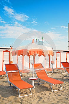 Orange umbrellas and chaise lounges on the beach of Rimini in It