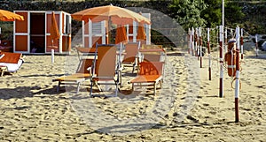 Orange umbrellas and chaise lounges on the beach of Vieste in Italy