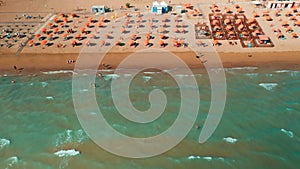 Orange umbrellas and sun lounges on sand beach near Venice