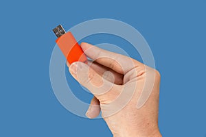 Orange USB flash memory on hand with isolated blue background