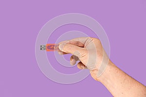 Orange USB flash memory on hand with isolated violet background