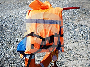 Orange vest hanging over a lifebuoy on a pebble beach on a sunny day