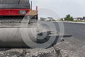 Orange Vibration roller compactor standing on a ground near asphalts road at road construction and repairing asphalt