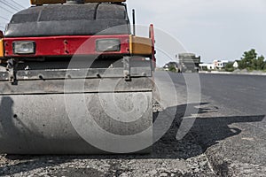 Orange Vibration roller compactor standing on a ground near asphalts road at road construction and repairing asphalt