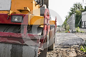 Orange Vibration roller compactor standing on a ground near asphalts road at road construction and repairing asphalt