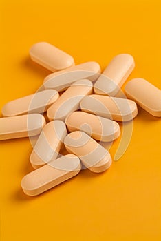 Orange vitamin pills on an orange background