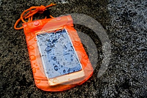 Orange waterproof mobile phone case with water droplets.PVC zip lock bag protect mobile phone or important items from water. photo