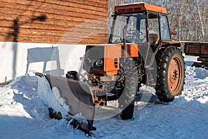 Wheeled snow plow tractor with blade in winter