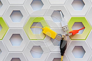 Orange, white, black and yellow USB connectors on white and green honeycomb background