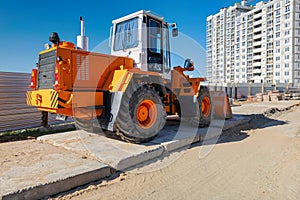 An orange and white construction vehicle is stationed on the side of a road, ready for work