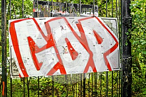 Orange and white graffiti on a black metal fence