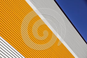 Orange and white metal panel construction, wall of building with blue sky