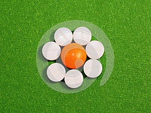 Orange and white tablets on a green background