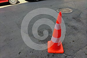 Orange and white traffic cone to indicate or signal that there is some kind of restriction, a ban on stopping, parking