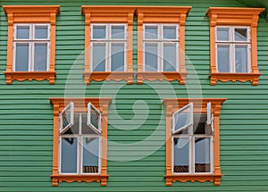 Orange windows on the green wall of green wooden house, Norway