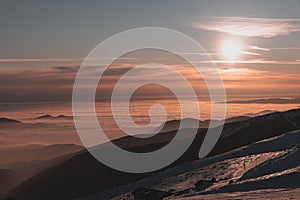 Orange winter sunset above clouds during inversion weather