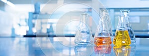 Orange yellow solution in science glass flask win blue chemistry laboratory banner background
