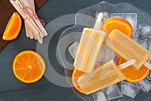 Orange yogurt popsicles in an ice filled bowl