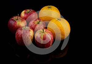 Oranges and Apple Fruits on a Reflective Black Surface