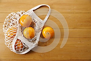 Oranges in Cotton mesh grocery bag on wooden background