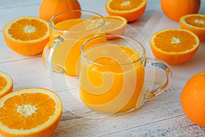 Oranges and fresh squeezed orange juice close up on wooden background