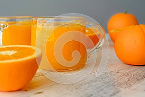 Oranges and fresh squeezed orange juice close up on wooden background