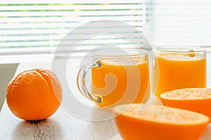 Oranges and fresh squeezed orange juice close up on wooden background