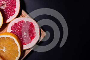 Oranges fruit on black wooden boards. Halves of juicy orange on black background. Orange fruit, citrus minimal concept. Top view,