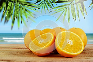 Oranges fruit on wooden table and blur beach background.