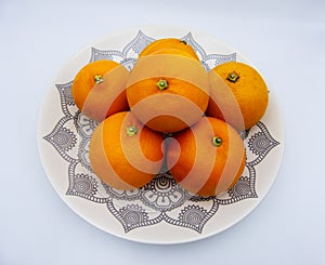 Oranges group on a plate, white background