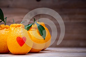 Oranges have a red heart-shaped put on the wooden table
