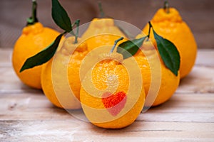 Oranges have a red heart-shaped put on the wooden table