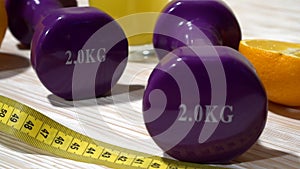 Oranges, juice, dumbbells and measuring tape on wooden background.